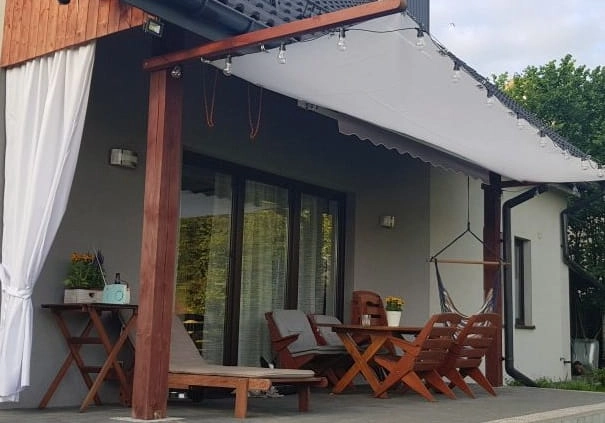 Toldo vela extensible 3x5 m instalado en una estructura de madera en una terraza con muebles de exterior