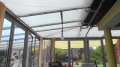 Voile d'ombrage rectangulaire blanc 3,2x2,5 m monté sous le toit en verre d'une orangerie moderne