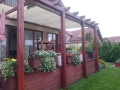 Voile d'ombrage de jardin blanche 3,2x2,5 m montée sur une pergola en bois au-dessus d'une terrasse fleurie