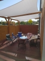 Toldo de vela cuadrado impermeable 4x4 m instalado sobre una terraza con muebles de jardín junto a la casa