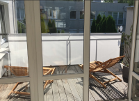 Biała osłona balkonowa o wymiarach 0,9x5m zamontowana na balustradzie tarasu z drewnianymi leżakami