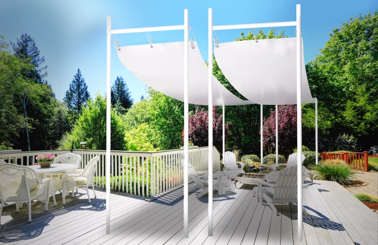 Voile d'ombrage romain blanc installé sur une terrasse en bois avec mobilier de jardin et vue sur la forêt